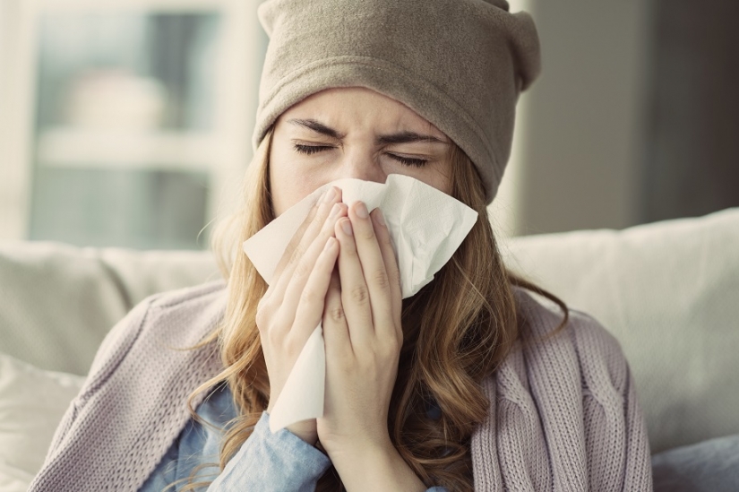 Mujer con gripe o resfriado sonándose la nariz